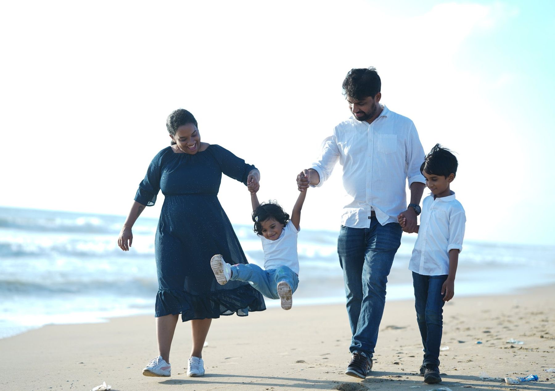 Family swinging their little one on the beach