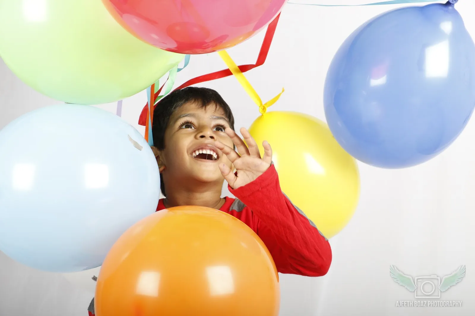 Boy laughing among colourful balloons, birthday photoshoot — kids and baby photography by Ajeeth Boaz Photography, Chennai