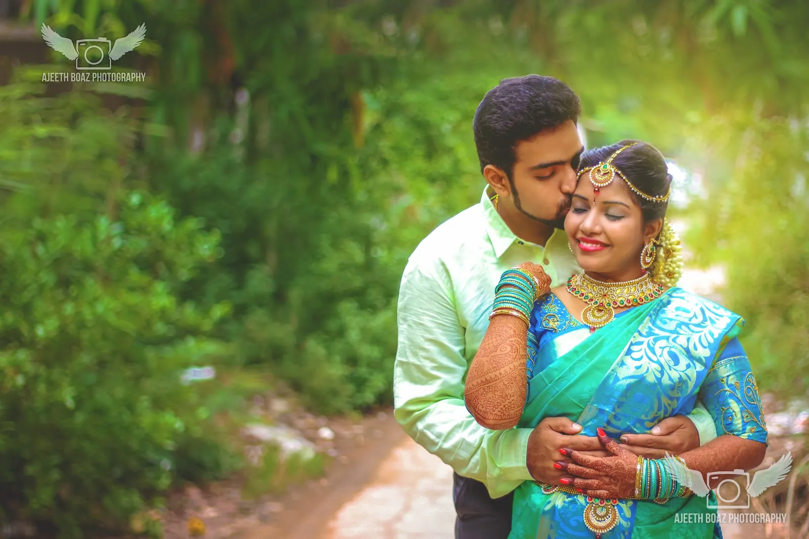 Couple embracing among the trees, bride in a teal silk saree — candid wedding photography by Ajeeth Boaz Photography, Chennai